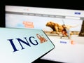 Mobile phone with logo of Dutch financial services company ING Groep N.V. on screen in front of website.