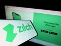 Mobile phone with logo of fintech Zilch Technology Limited (PayZilch) on screen in front of business website.