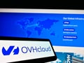 Mobile phone with logo of French cloud computing provider OVH Groupe SAS on screen in front of website.