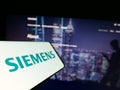 Mobile phone with logo of German conglomerate Siemens AG on screen in front of business website.