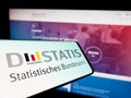 Mobile phone with logo of German Statistisches Bundesamt (Destatis) on screen in front of website.