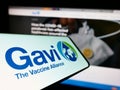 Mobile phone with logo of health partnership Gavi, the Vaccine Alliance on screen in front of website.