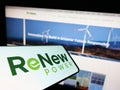 Mobile phone with logo of Indian company ReNew Energy Global plc on screen in front of business website.