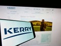 Mobile phone with logo of Irish food company Kerry Group plc on screen in front of business website.