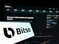Mobile phone with logo of Mexican cryptocurrency exchange Bitso on screen in front of business website.