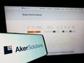 Mobile phone with logo of Norwegian engineering company Aker Solutions ASA on screen in front of website.