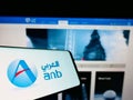 Mobile phone with logo of Saudi Arabian financial company Arab National Bank on screen in front of website.