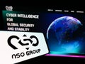 Mobile phone with logo of technology company NSO Group Technologies Ltd. on screen in front of website.