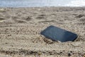 Mobile phone lying on the beach in the sand. weatherproof phones, lost phone concept