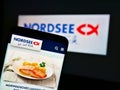 Mobile phone with meal of German fast-food restaurant chain Nordsee GmbH on display in front of company logo.