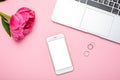 Mobile phone mock up and peony flower on pink pastel table in flat lay style. Woman working desk.Summer colour