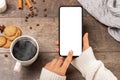 Mobile phone mockup in a cafe in winter. Mockup image of woman`s hands holding cellphone with blank screen and white coffee cups Royalty Free Stock Photo