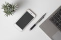 Mobile phone mockup, top view of White office desk table with mockup blank screen smartphone and computer laptop. Flat lay top