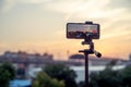 Mobile phone mounted on a tripod at full extention replacing a DSLR for a professional shoot to capture a sunset with a