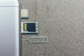 Mobile phone and open slots for nano SIM cards, micro SD drive and metal key on grey background Royalty Free Stock Photo