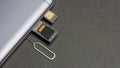 Mobile phone and open slots for nano SIM cards, micro SD drive and metal key on grey background Royalty Free Stock Photo