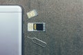 Mobile phone and open slots for nano SIM cards, micro SD drive and metal key on grey background Royalty Free Stock Photo