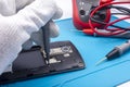 Mobile phone repair. The service technician disassembles the phone on the esd mat with a screwdriver