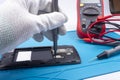 Mobile phone repair. The service technician disassembles the phone on the esd mat with a screwdriver