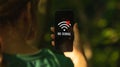 Mobile phone without signal, no service screen, girl in the forest with smartphone, searching for the help Royalty Free Stock Photo