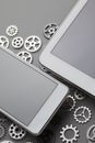 Mobile phone and small gears on gray table Royalty Free Stock Photo
