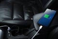 Mobile phone ,smartphone, cellphone is charged ,charge battery with usb charger in the inside of car. modern black car interior Royalty Free Stock Photo