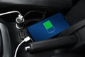 Mobile phone ,smartphone, cellphone is charged ,charge battery with usb charger in the inside of car. modern black car interior Royalty Free Stock Photo