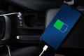 Mobile phone ,smartphone, cellphone is charged ,charge battery with usb charger in the inside of car. modern black car interior Royalty Free Stock Photo