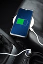 Mobile phone ,smartphone, cellphone is charged ,charge battery with usb charger in the inside of car. modern black car interior Royalty Free Stock Photo