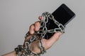 Mobile phone smartphone chained to hands with chains on a light background Royalty Free Stock Photo