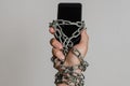 Mobile phone smartphone chained to hands with chains on a light background Royalty Free Stock Photo