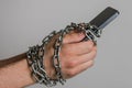 Mobile phone smartphone chained to hands with chains on a light background Royalty Free Stock Photo