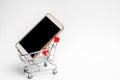 Mobile phone in a supermarket trolley. buying and selling a smartphone. online store. consumer credit. isolated white background Royalty Free Stock Photo