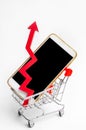 Mobile phone in a supermarket trolley and a red arrow up. high demand for the purchase of a smartphone. online store. consumer cre Royalty Free Stock Photo