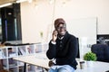 Mobile phone talk. Young black businessman has mobile phone call in modern office interior