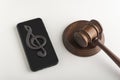 Mobile phone with treble clef sign on display and judges hammer. Illegal use of music concept. Digital piracy Royalty Free Stock Photo