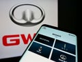 Mobile phone with webpage of car manufacturer Great Wall Motors Co. Ltd. (GWM) on screen in front of logo.