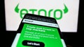 Mobile phone with webpage of Israeli social trading company eToro on screen in front of business logo.