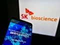 Mobile phone with webpage of South Korean biological company SK Bioscience Co. Ltd. on screen in front of logo.