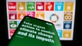 Mobile phone with webpage of UN Sustainable Development Goals (SDG) on screen in front of logo.