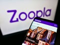 Mobile phone with website of British real estate platform Zoopla Limited on screen in front of business logo.