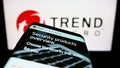 Mobile phone with website of cybersecurity company Trend Micro Inc. on screen in front of business logo.