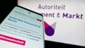 Mobile phone with website of Dutch regulator Autoriteit Consument en Markt (ACM) on screen in front of logo.