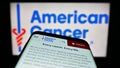 Mobile phone with website of organization American Cancer Society (ACS) on screen in front of logo.