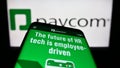 Mobile phone with website of payroll technology company Paycom Software Inc. on screen in front of logo. Royalty Free Stock Photo