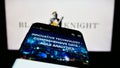 Mobile phone with website of US financial services company Black Knight Inc. on screen in front of logo.