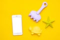 Mobile phone with white screen and plastic beach toy pastel color on yellow background. The development of fine motor Royalty Free Stock Photo