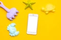 Mobile phone with white screen and plastic beach toy pastel color on yellow background. The development of fine motor Royalty Free Stock Photo