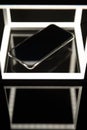 Mobile phone on wireless charger, black background with led lighting and reflections on the glass surface. Digital art.