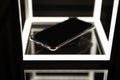 Mobile phone on wireless charger, black background with led lighting and reflections on the glass surface. Digital art. Royalty Free Stock Photo